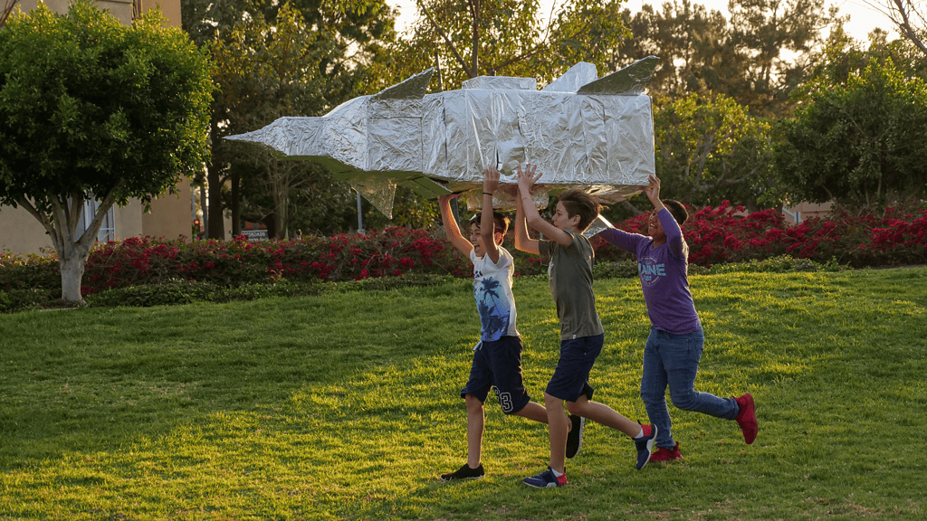 three kids running with tinfoil spaceship