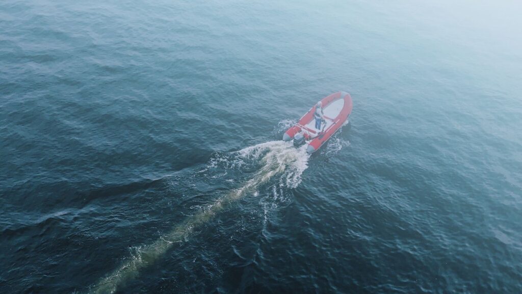 aerial shot of person driving boat into fog