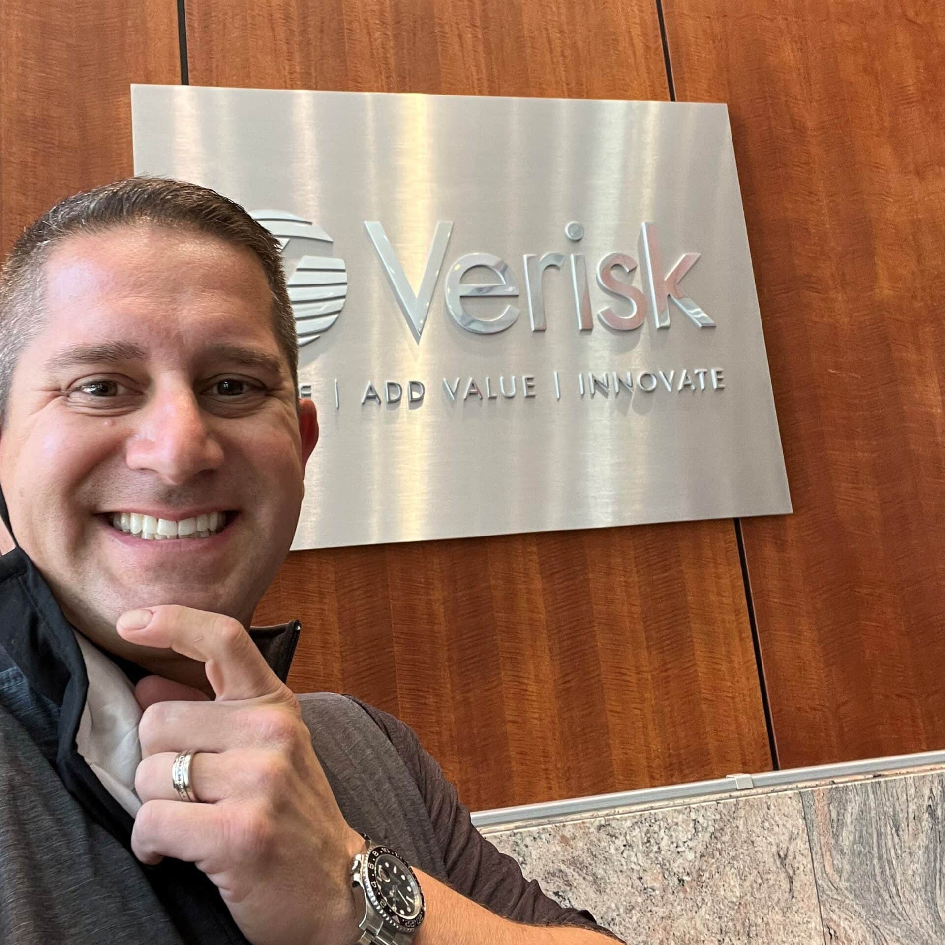 Infutor SEO Gary Walter standing next to a Verisk sign and smiling