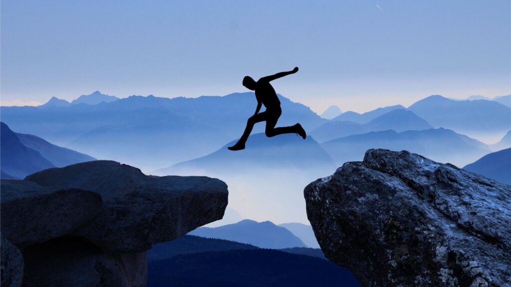 Person jumping between cliffs