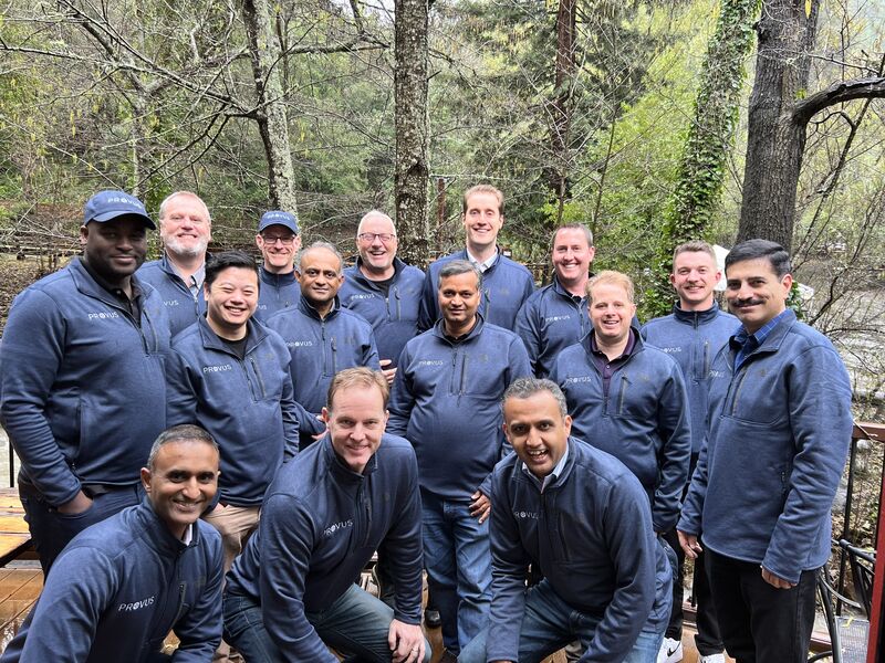 Photo of Provus team members wearing blue pullovers in a wooded area