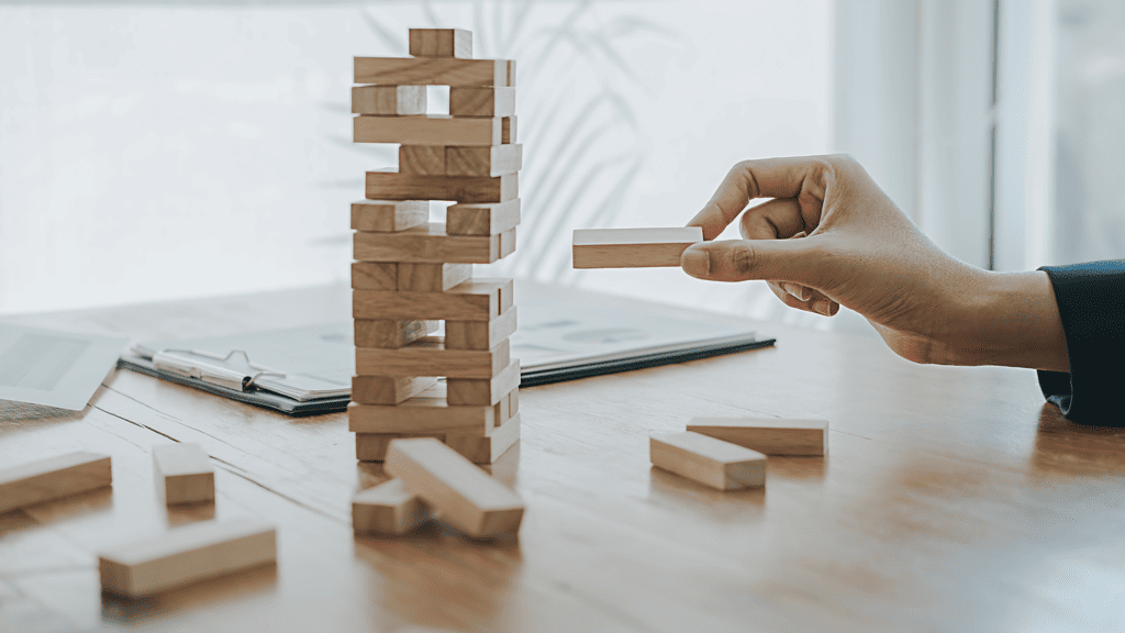 a person pulling a wooden block out of a Jenga tower