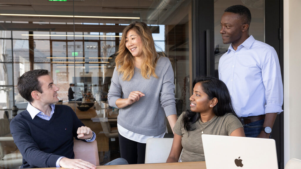 co-workers gathered around table with laptop