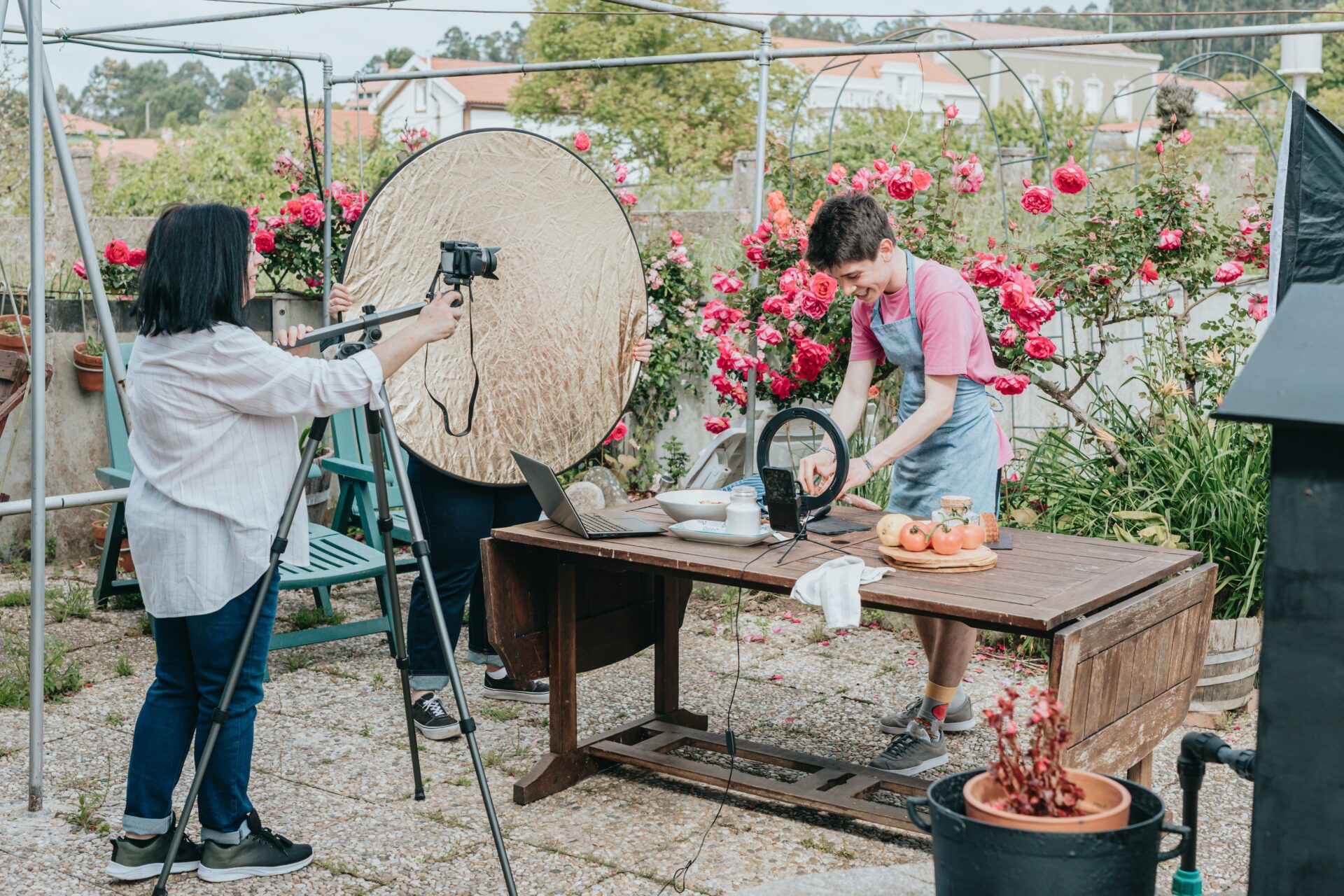 A man sets up a table to cook while women films him.
