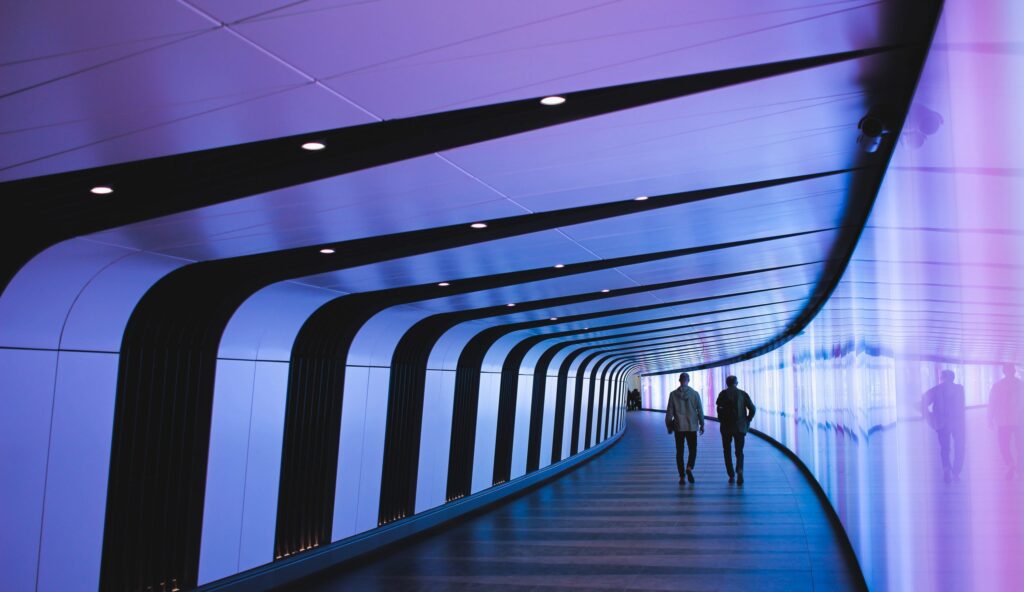 men walking down neon hallway